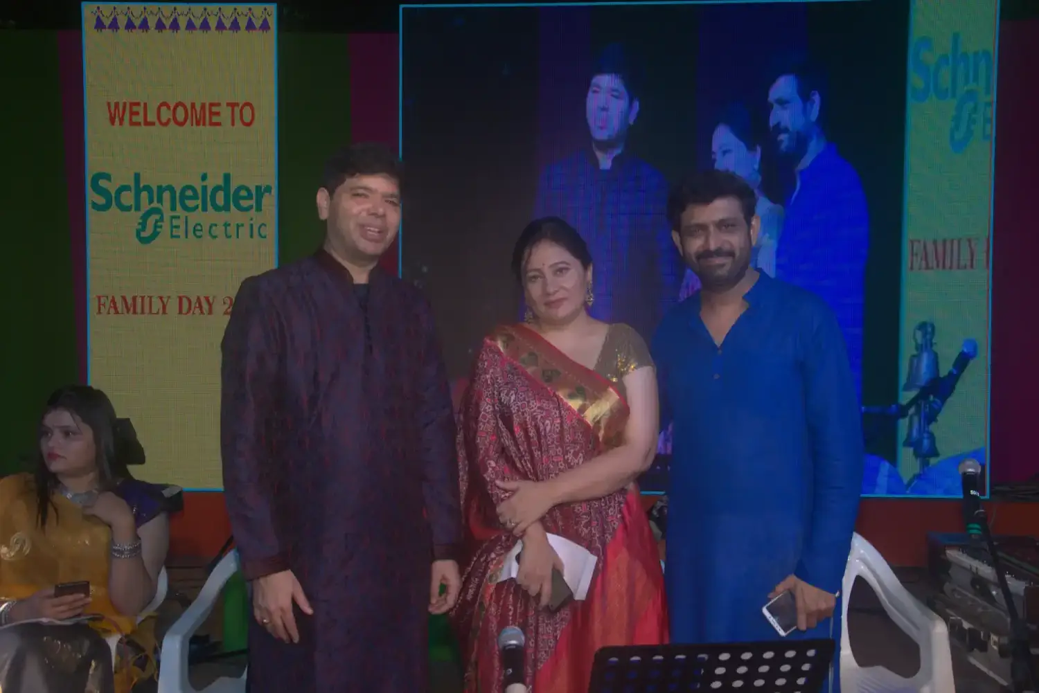 Man and woman speaking on stage at night with blue lighting
